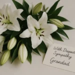 White funeral flowers with a sympathy card for grandad